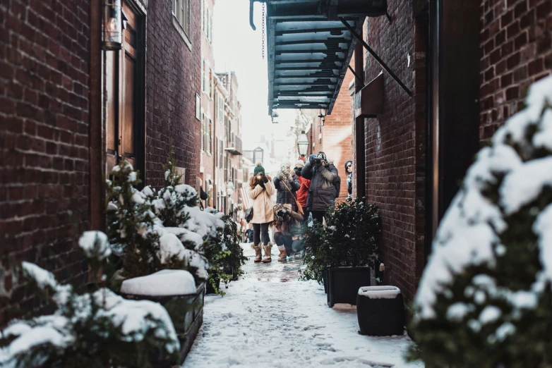 several people are walking down the snowy alley