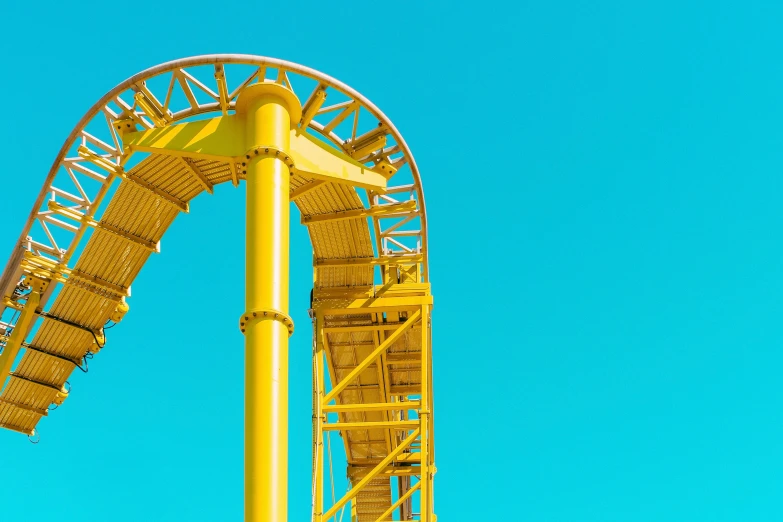 a tall yellow roller coaster against a blue sky