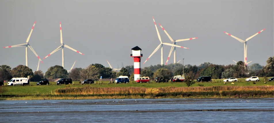 a lighthouse in front of multiple wind mills