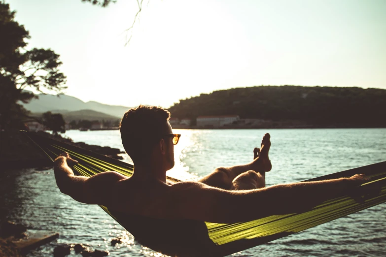 a man relaxing in a hammock by a lake