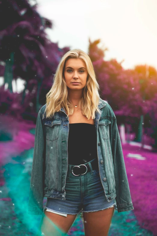 a beautiful blond woman standing in front of trees and grass