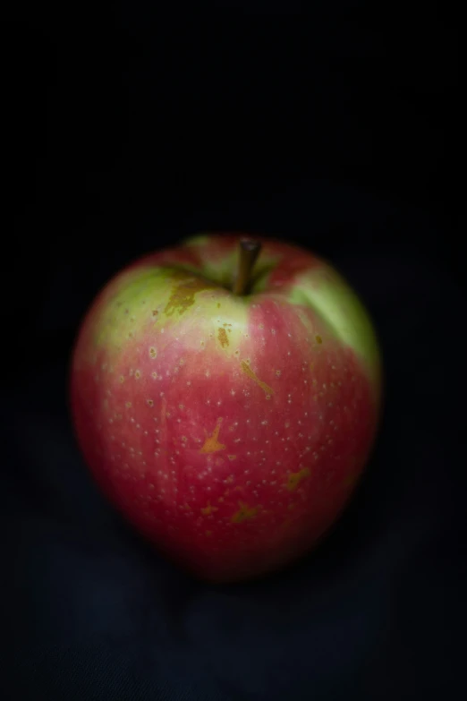 an apple sitting in the dark on a table