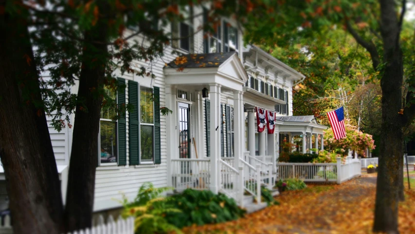 a large white house with green shutters and an american flag