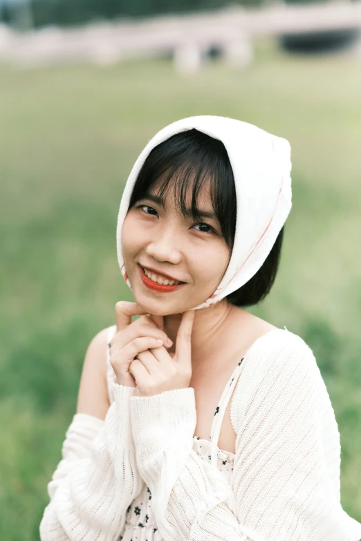 a woman wearing a white hat sitting on top of a green field