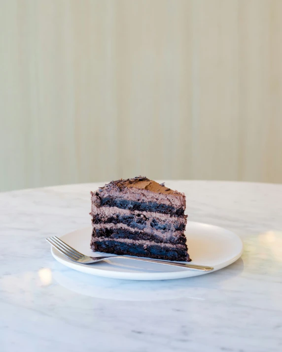 piece of chocolate cake sitting on white plate next to fork