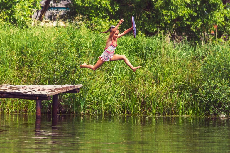 a girl jumps into the water with a kite