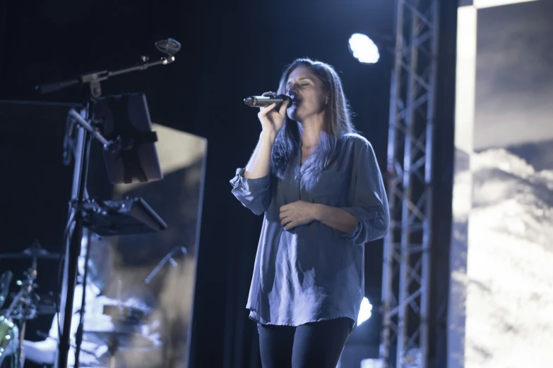 a woman standing on a stage holding a microphone