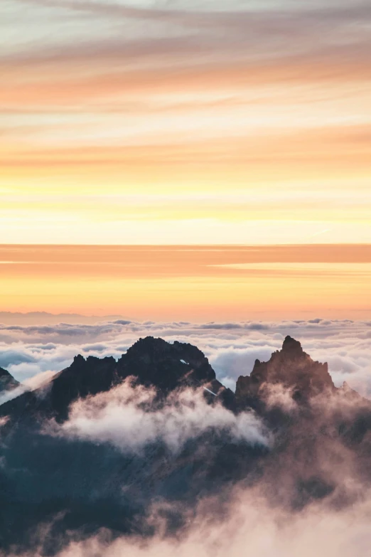 two large rocks with tops high above the clouds