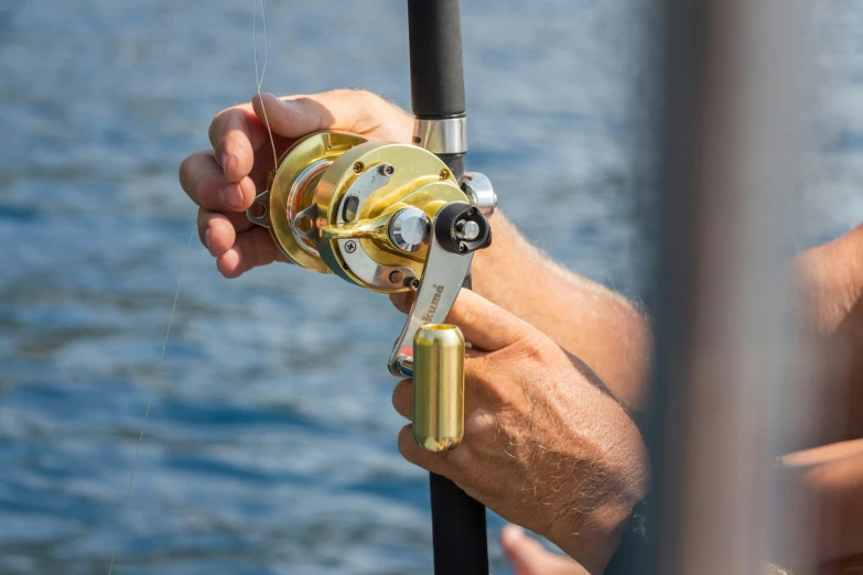 a hand holding a fishing rod with a boat in the background