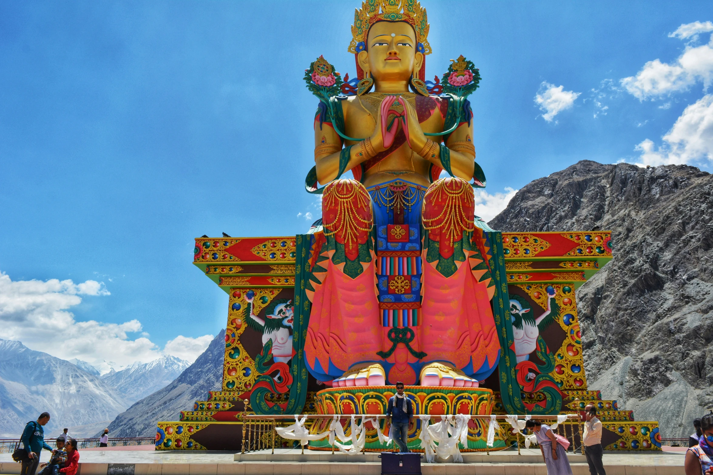 a giant statue is sitting with mountains in the background