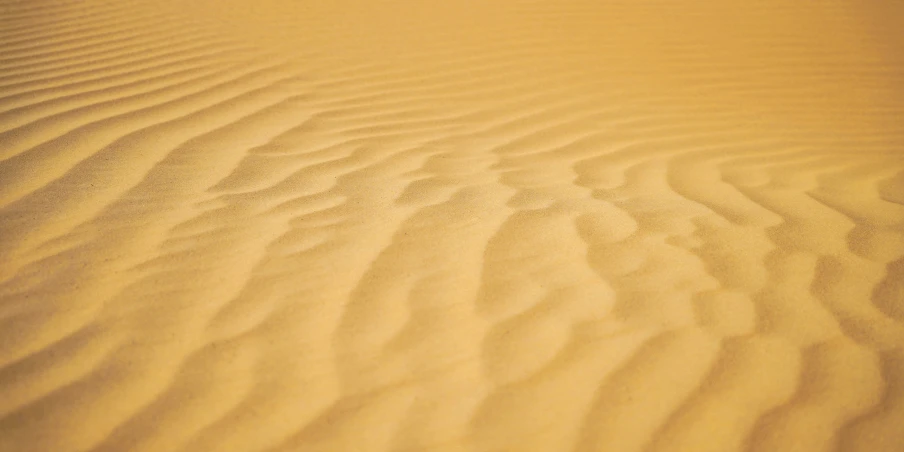 a beach sand dune with little ripples, in the distance