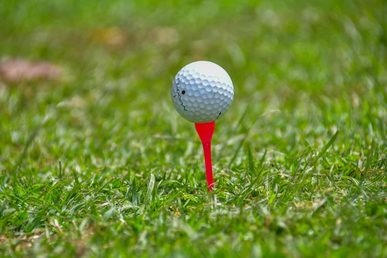 a golf ball on a red tee with a blurry background