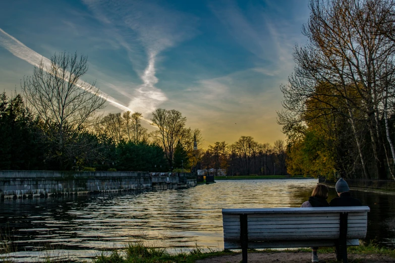 the people sit on the bench beside the water