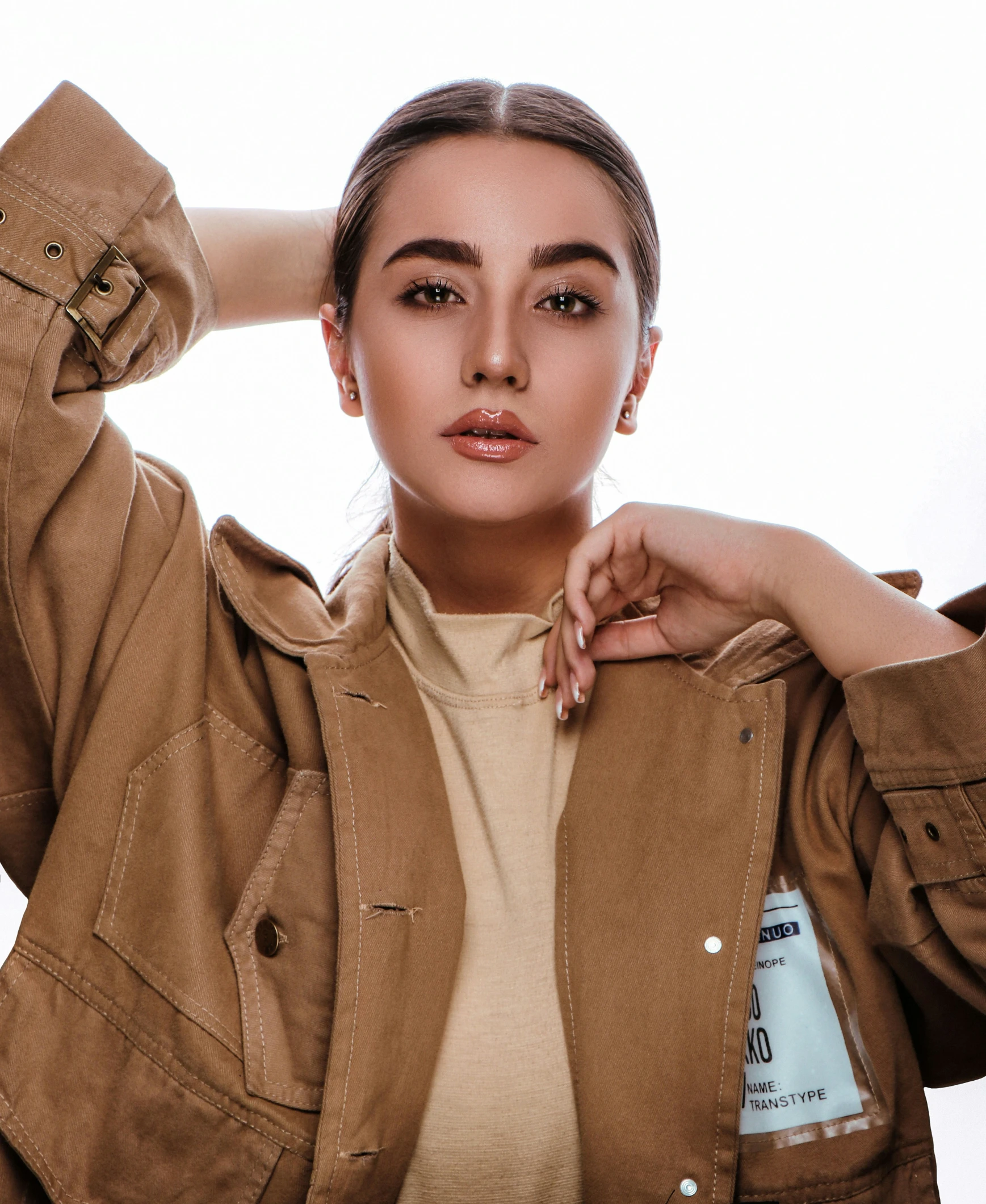 young woman wearing a brown jacket looking at camera