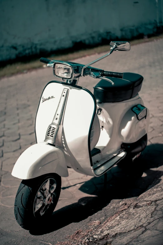 the white scooter is sitting on the pavement