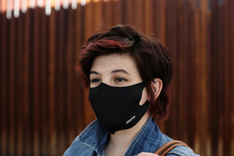 a woman in denim jacket and black mask with an embroidered face covering