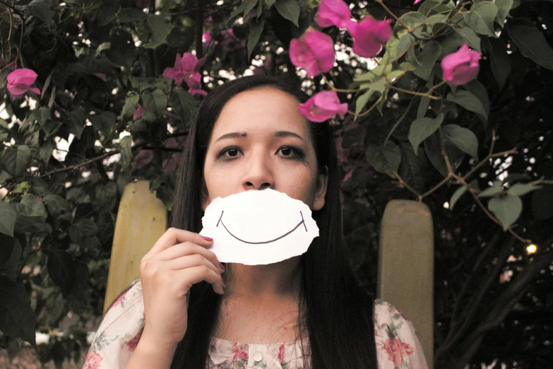 a girl holding up a piece of paper with a smiley face