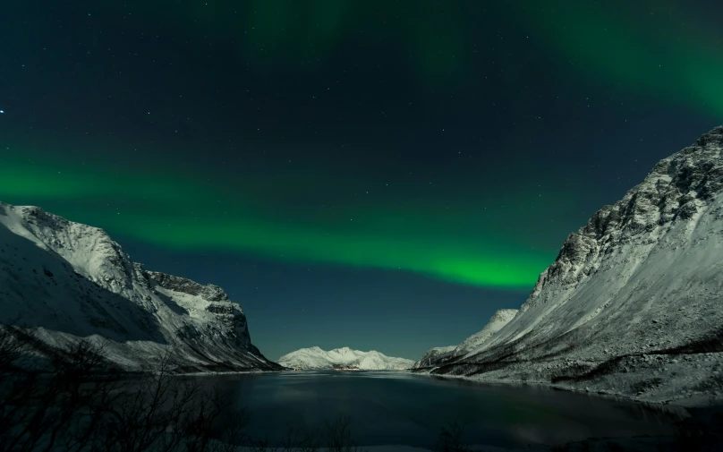 two mountains next to a lake with the northern lights in the sky