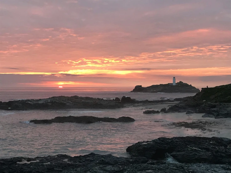 the view of the ocean with a lighthouse and cloudy sky