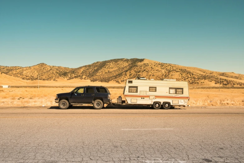 an rv parked beside a truck on the side of the road