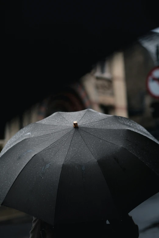 a person is walking down the street holding a black umbrella