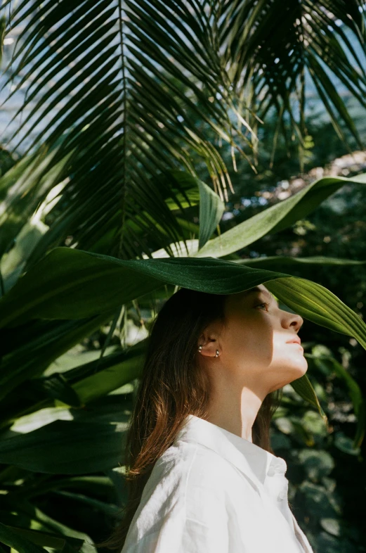 a woman with a white shirt and black hat under a palm tree