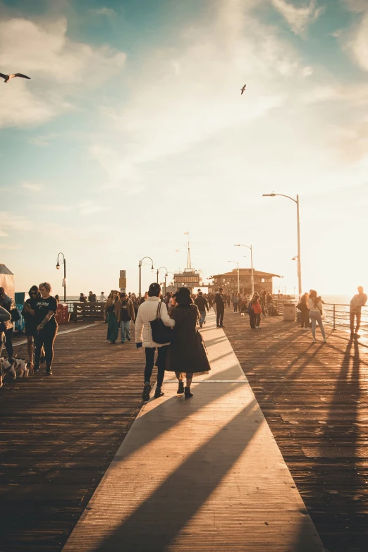 people are walking along the pier near boats