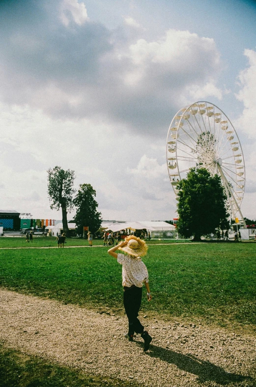 a person in a hat standing near a ferris wheel