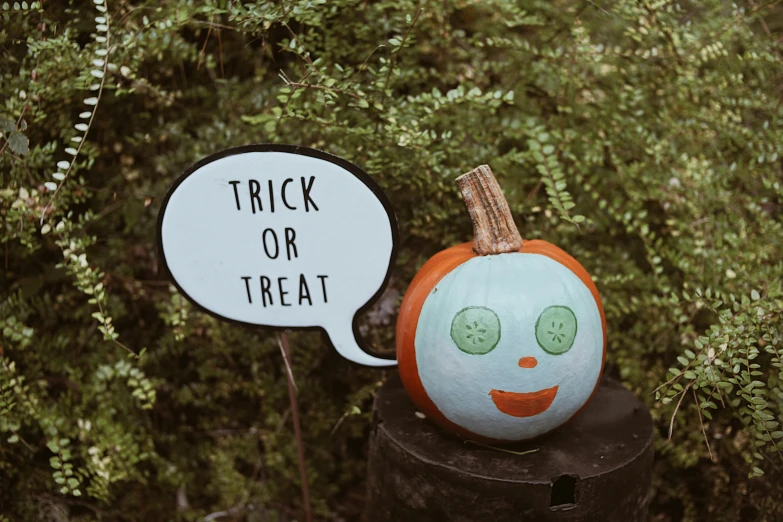 a pumpkin is sitting on a stump and next to an ornament with a speech bubble