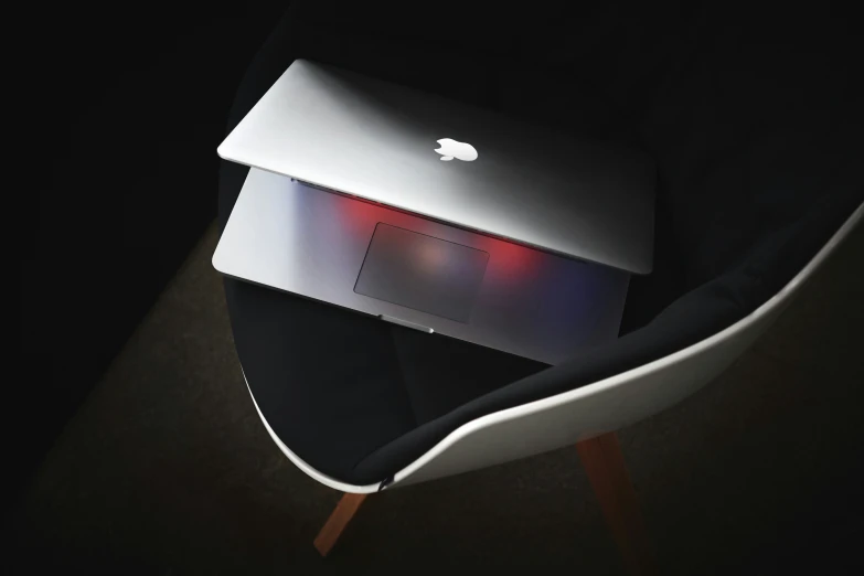 apple laptop with red light up lid sitting on top of a chair