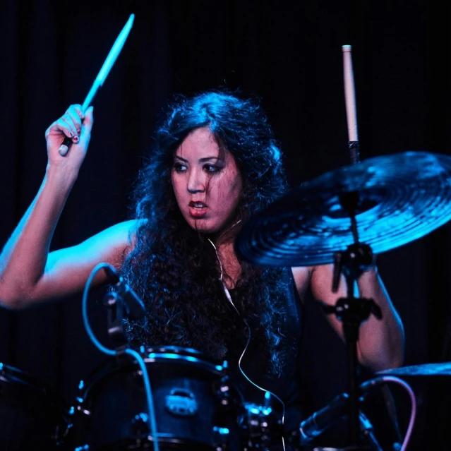 a woman with a microphone is drumming