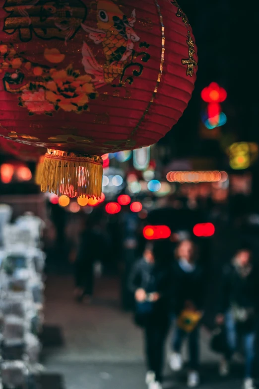 an oriental lantern hanging over some people on the sidewalk