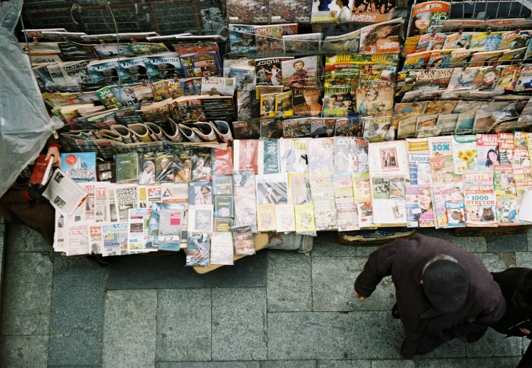 a man walking past an outdoor news stand