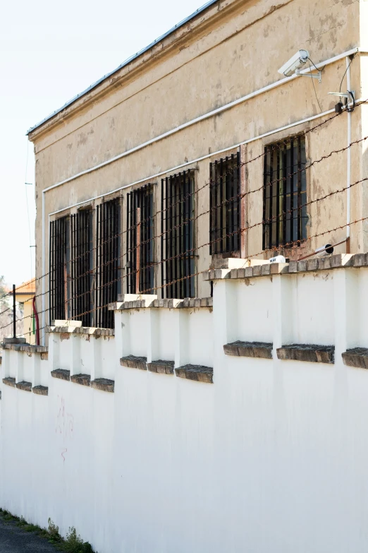 a long white fenced area that has several bars and windows