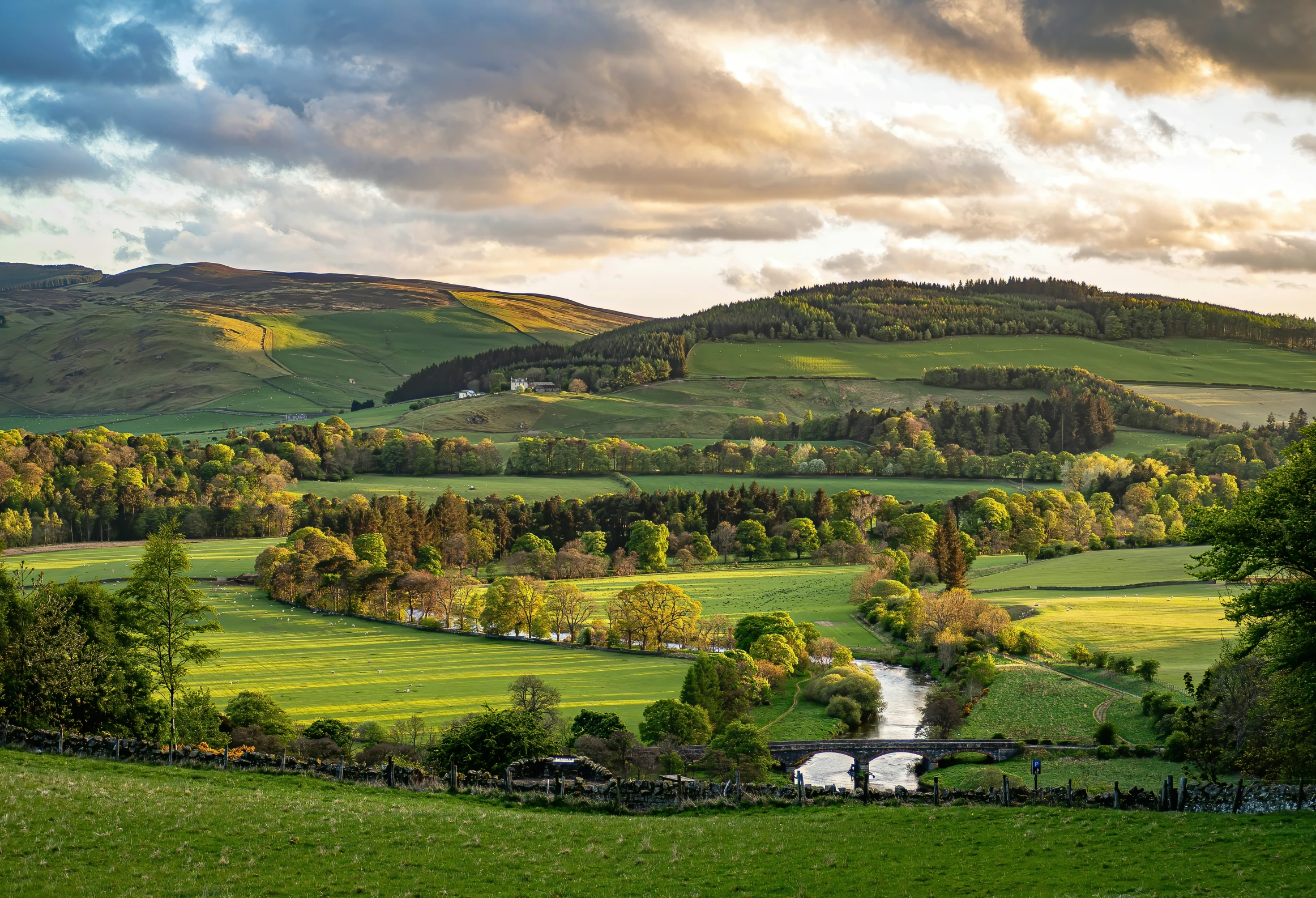 a lush green hillside sitting below a cloudy sky