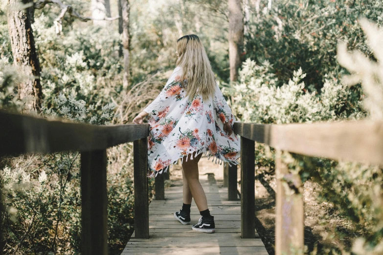 a woman walking across a bridge in the woods