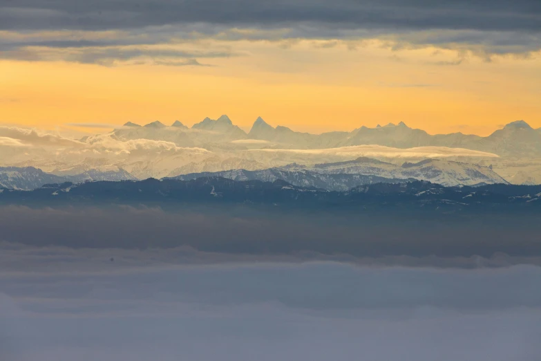 the view of mountains from above, with clouds in the sky