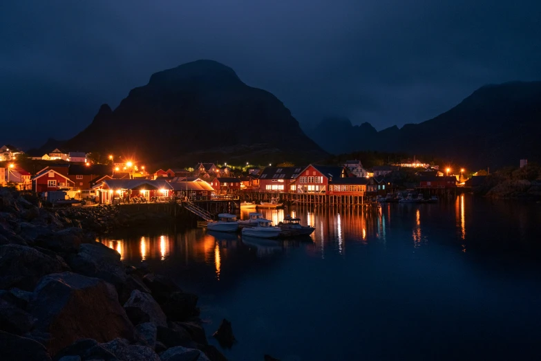 a village on a lake is at night, lit up by brightly colored lights