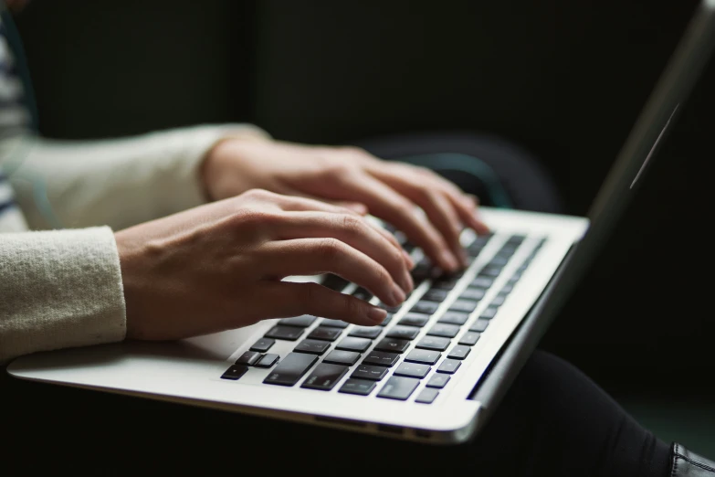 a person is typing on a white computer