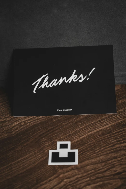 a black thank card and a pixel sticker on a table
