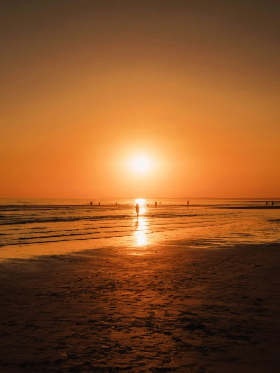 a couple of surfers are out on the ocean at sunset