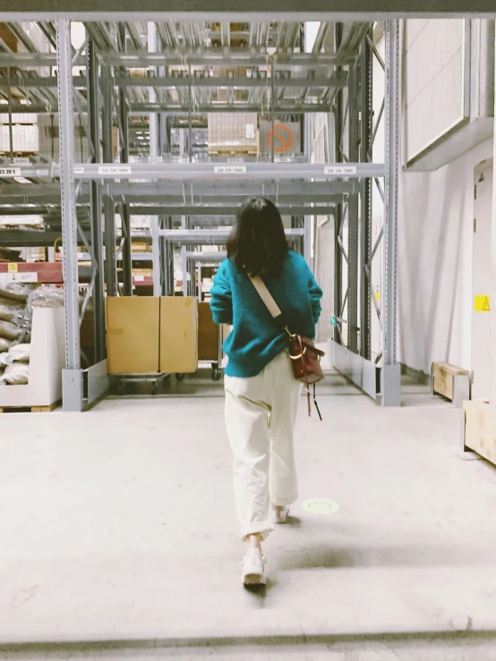 a woman walking through a warehouse carrying a handbag