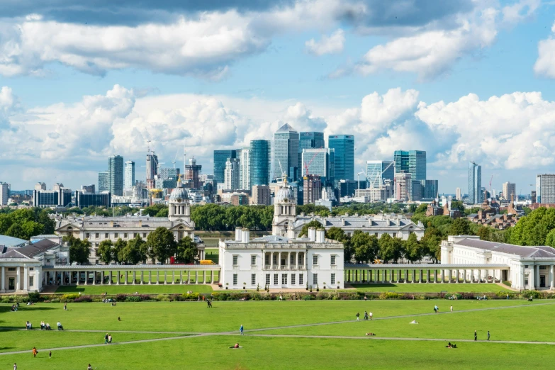 a beautiful cityscape with some buildings and people on the grass