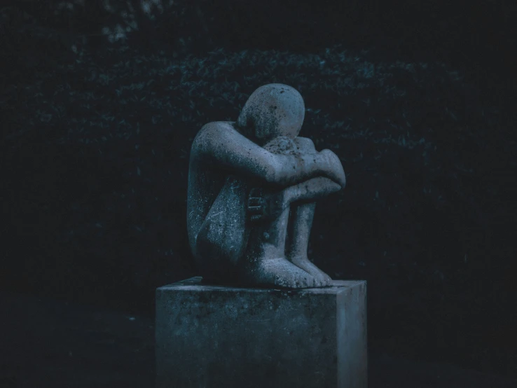 the statue is sitting alone on a bench