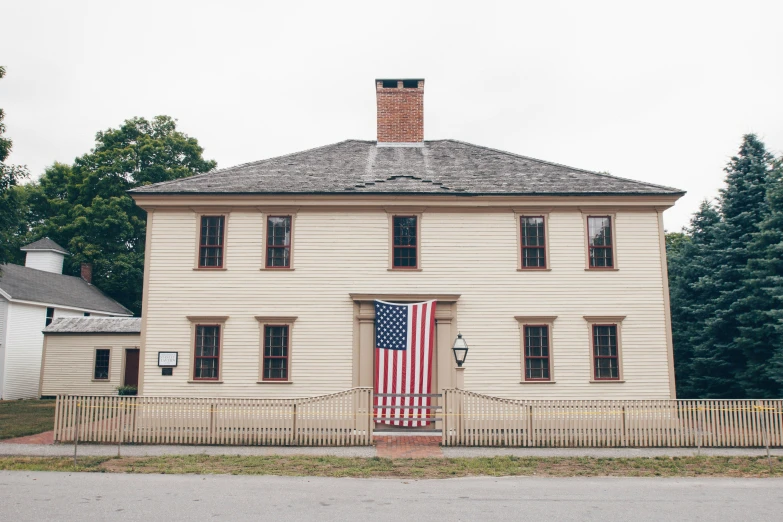 an old house that is painted white and has a flag on the door