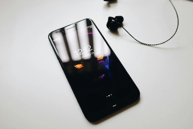 earphones, smartphone and head phones sitting on top of a table