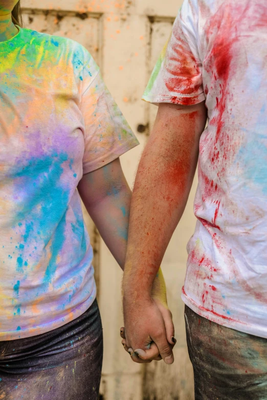 two people with colorful paint on their faces holding hands