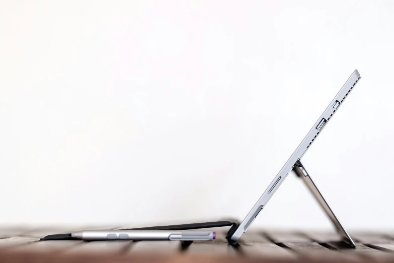 an apple laptop on the table with a pen laying on it