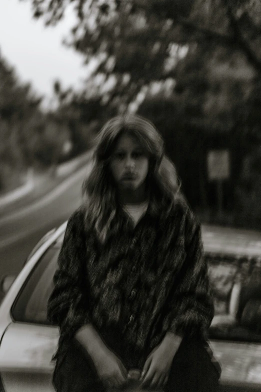 the woman is sitting on the bench by the car