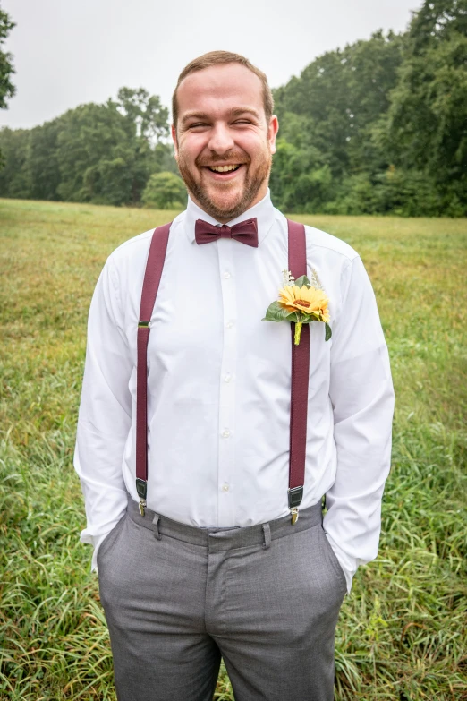 the man is wearing suspenders and has a flower in his pocket